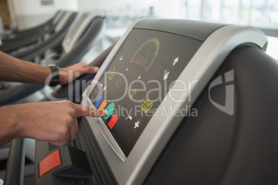 Man adjusting settings on the treadmill