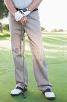 Lower half of golfer standing with club