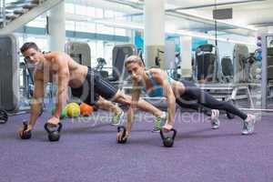 Bodybuilding man and woman lifting kettlebells in plank position