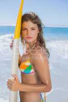 Beautiful surfer girl standing on the beach with her surfboard