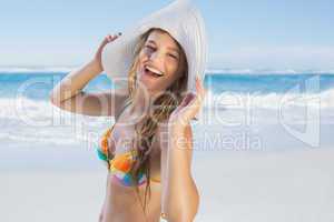 Beautiful girl on the beach laughing in white straw hat and biki