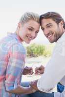 Happy couple smiling at camera holding wine glasses