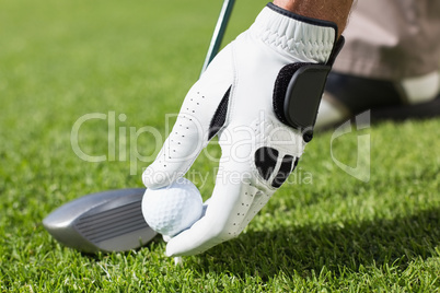 Golfer placing golf ball on tee