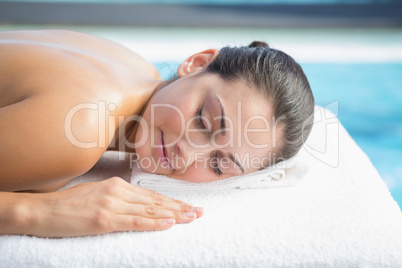 Calm brunette lying on massage table poolside