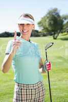 Female golfer standing and pointing up