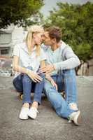 Hip young couple sitting on skateboard kissing