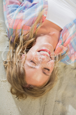Pretty blonde smiling at the beach lying on the sand