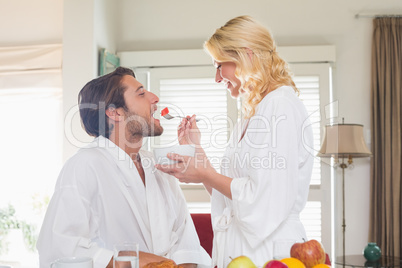 Cute couple in bathrobes having breakfast together