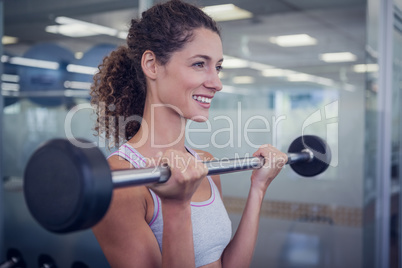 Fit smiling woman lifting barbell