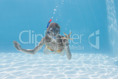 Cute blonde underwater in the swimming pool with snorkel and sta