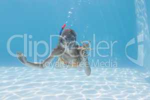 Cute blonde underwater in the swimming pool with snorkel and sta
