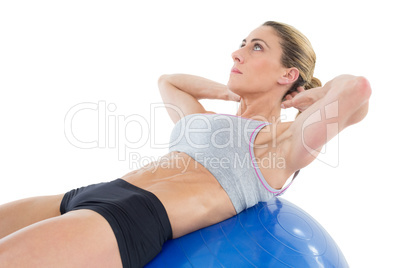 Fit woman doing sit ups on blue exercise ball