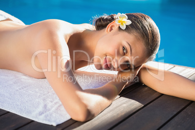 Smiling brunette lying on a towel poolside