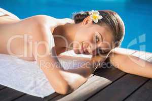 Smiling brunette lying on a towel poolside