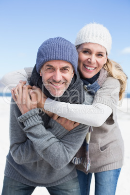 Attractive couple hugging and smiling at camera on the beach in