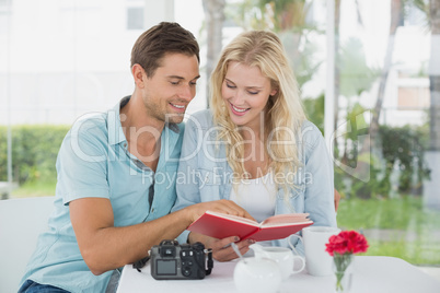 Cute hipster couple reading book together at table