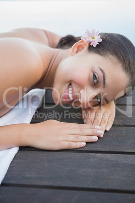 Peaceful brunette lying on towel smiling at camera