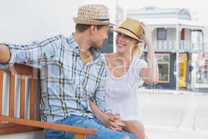 Young hip couple sitting on bench smiling at each other