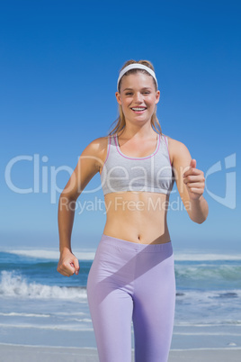 Sporty happy blonde jogging on the beach