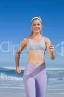 Sporty happy blonde jogging on the beach