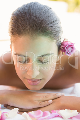 Calm brunette lying on towel with rose petals