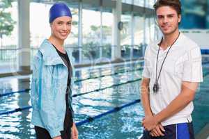 Pretty swimmer smiling at camera by the pool with her coach