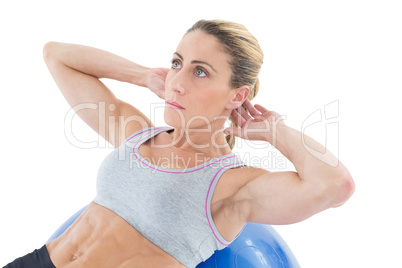 Fit woman doing sit ups on blue exercise ball