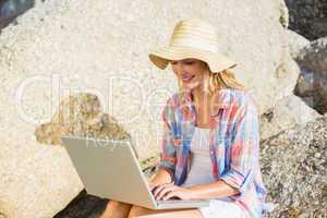 Pretty blonde using laptop at the beach