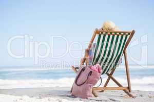 Woman sitting on beach in deck chair