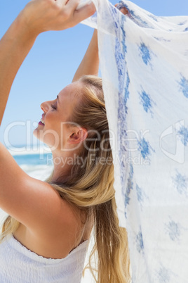 Pretty carefree blonde posing on the beach with scarf