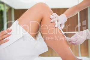 Woman getting her legs waxed by beauty therapist