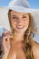 Beautiful girl in bikini and straw hat on the beach smiling at c