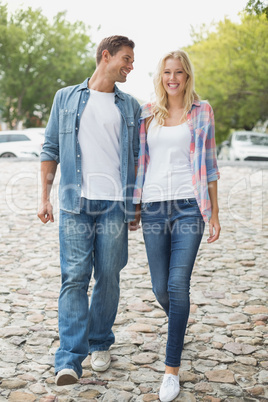 Hip young couple walking holding hands