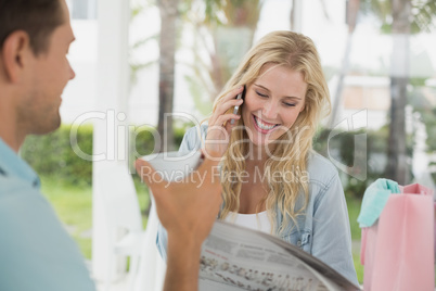 Pretty blonde talking on phone while having coffee with boyfrien