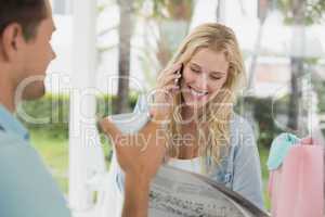 Pretty blonde talking on phone while having coffee with boyfrien