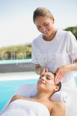 Tranquil brunette getting a head massage poolside