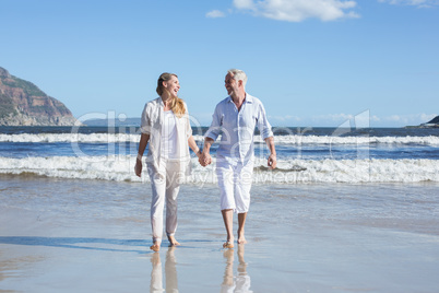 Happy couple walking barefoot on the beach