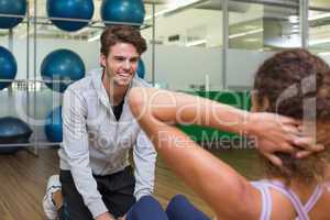 Trainer helping his client doing sit ups