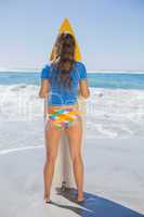 Fit surfer girl standing on the beach with her surfboard