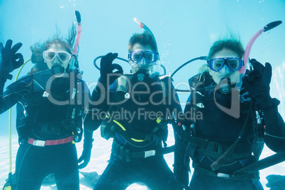Friends on scuba training submerged in swimming pool looking to