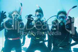 Friends on scuba training submerged in swimming pool looking to