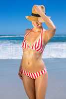 Gorgeous fit woman in bikini and sunhat posing on the beach