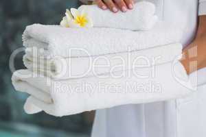 Beauty therapist holding pile of fresh white towels