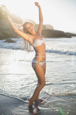 Beautiful laughing blonde in white bikini at the beach with wet