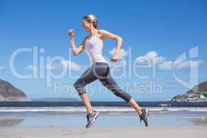 Pretty fit blonde jogging on the beach