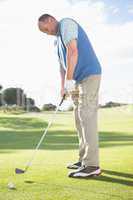 Golfer putting ball on the green