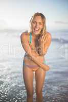 Happy blonde smiling at camera in bikini at the beach