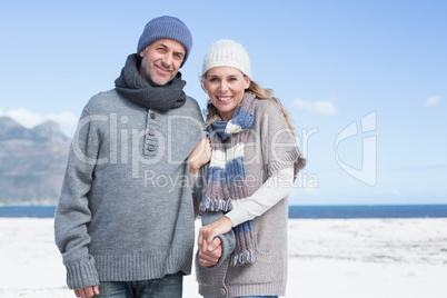 Smiling couple standing on the beach in warm clothing