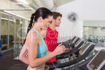 Fit couple running together on treadmills