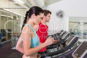 Fit couple running together on treadmills